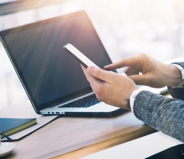 person using phone and laptop